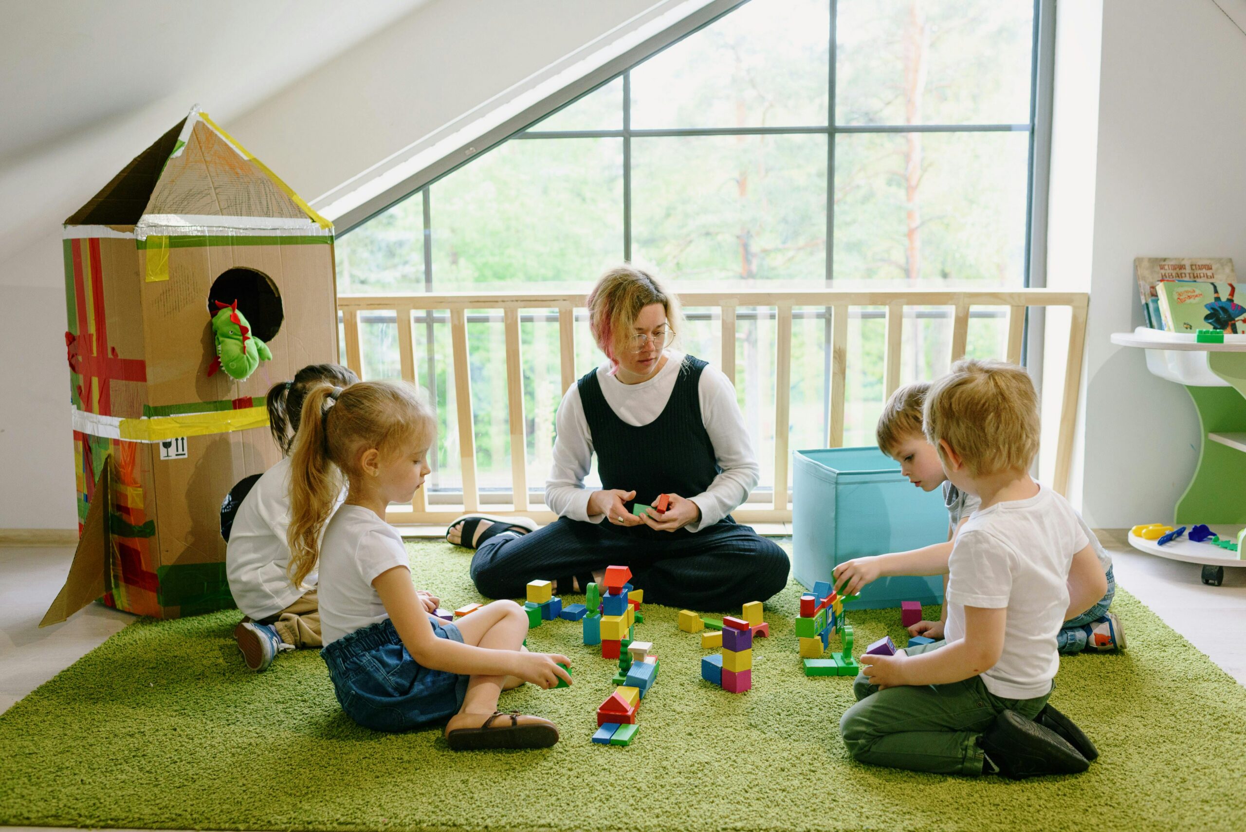 Children and carer sitting on green carpet