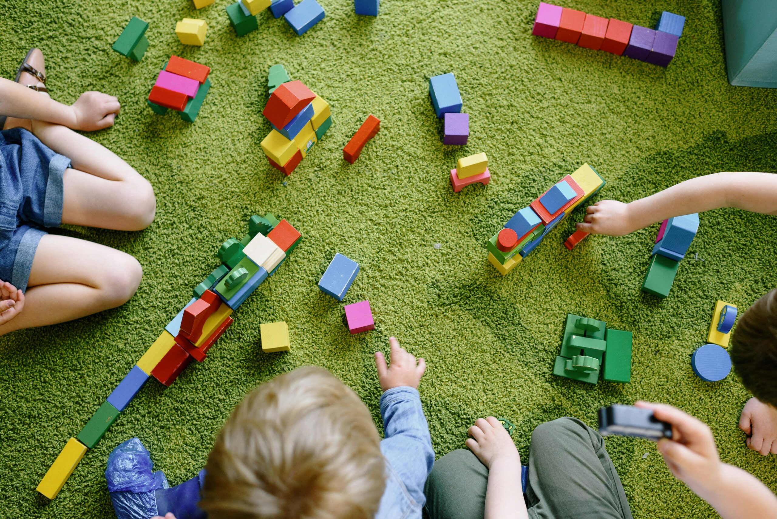 Children playing with blocks on green carpet