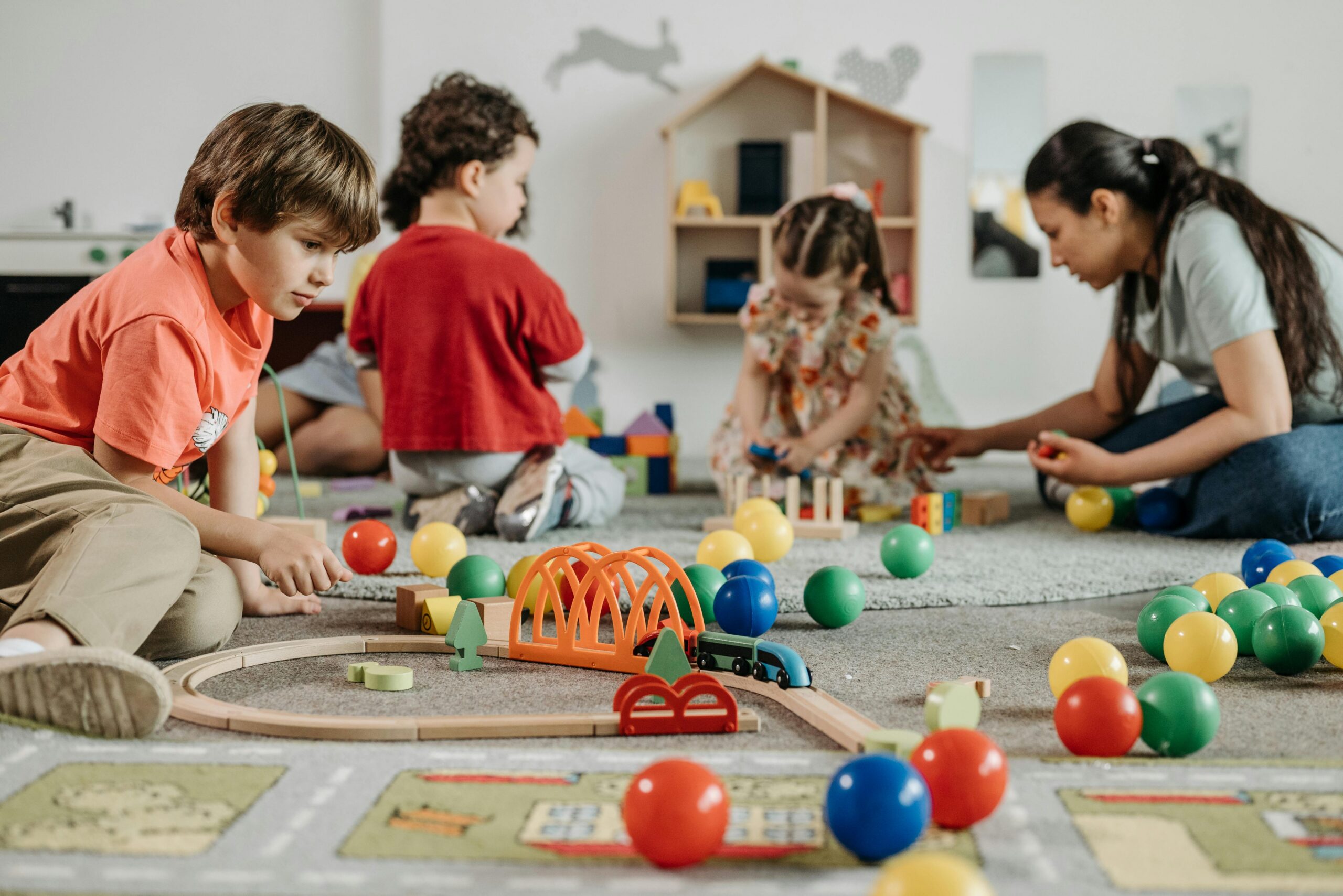 Children playing with toy train set and balls
