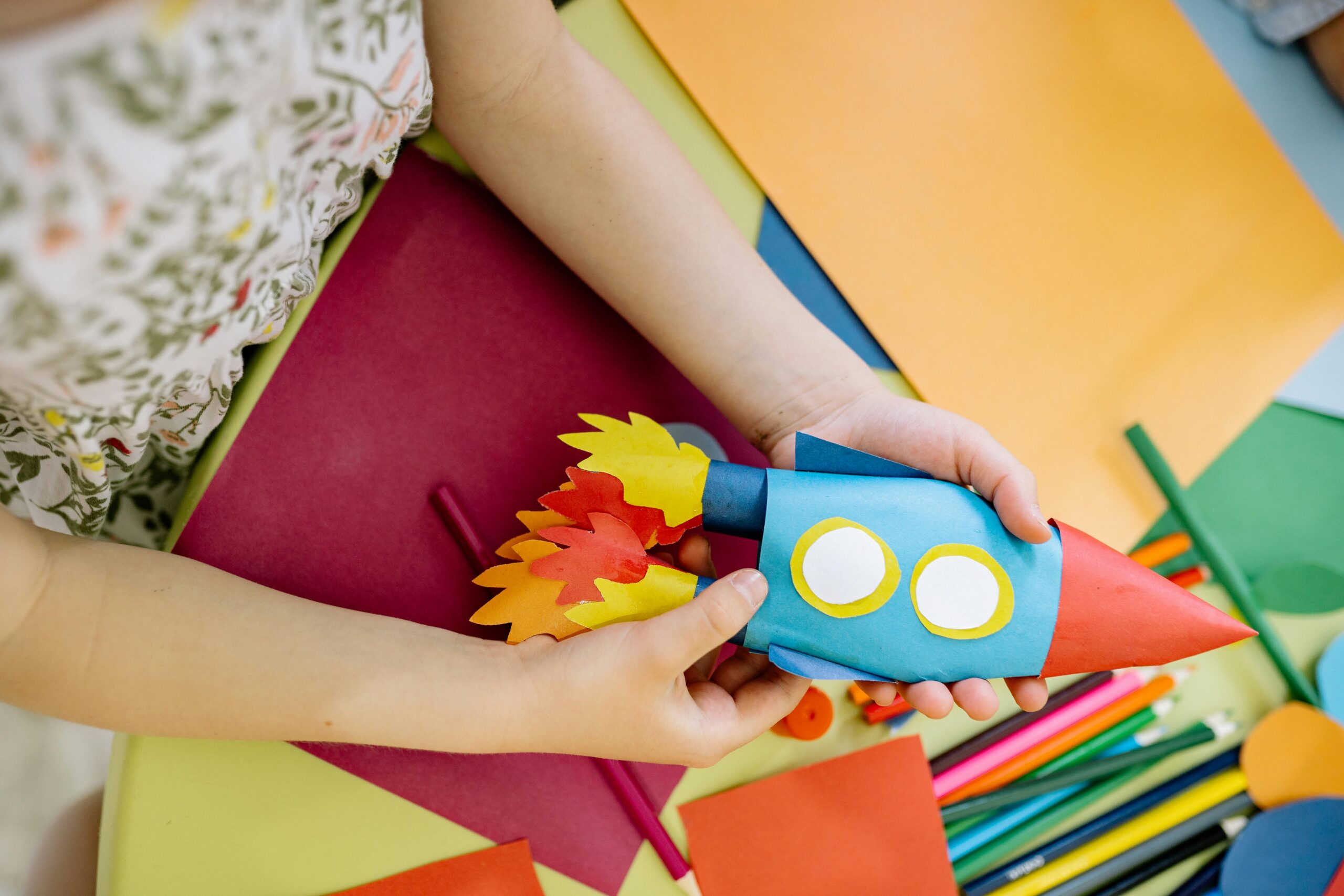 Child holding colourful paper rocket ship