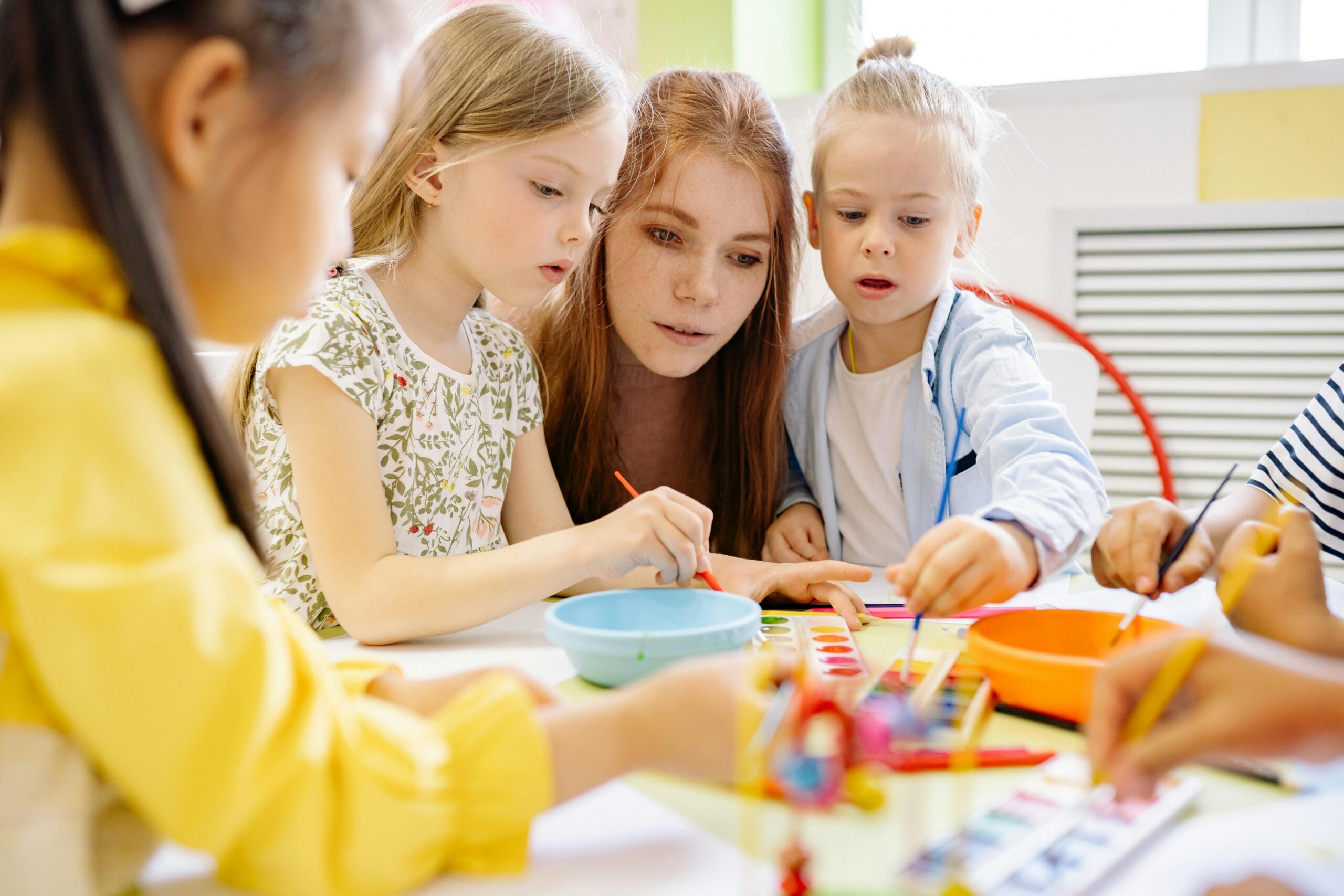 Carer sitting with children as they're drawing